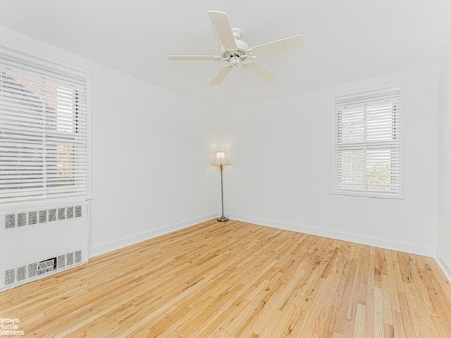 unfurnished room with light wood-type flooring, baseboards, plenty of natural light, and radiator heating unit