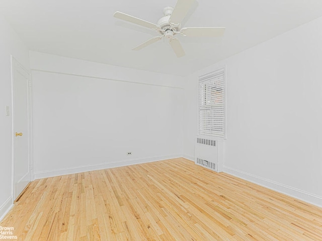 empty room with a ceiling fan, light wood-type flooring, radiator, and baseboards