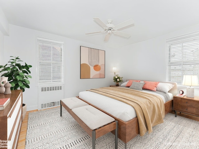 bedroom with radiator heating unit, a ceiling fan, and light wood-style floors