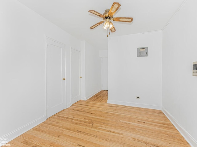 empty room featuring ceiling fan, light wood finished floors, and baseboards