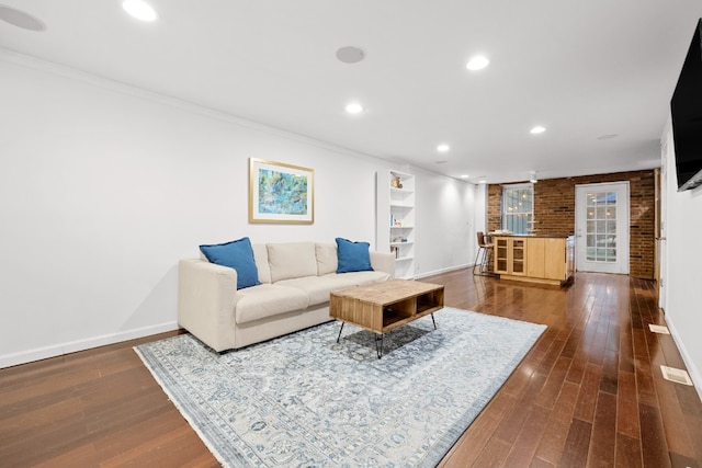 living room with brick wall, ornamental molding, and hardwood / wood-style floors