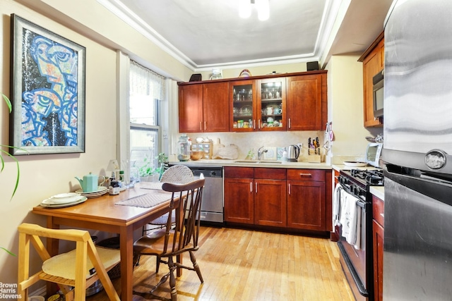 kitchen featuring light wood-type flooring, appliances with stainless steel finishes, sink, and ornamental molding