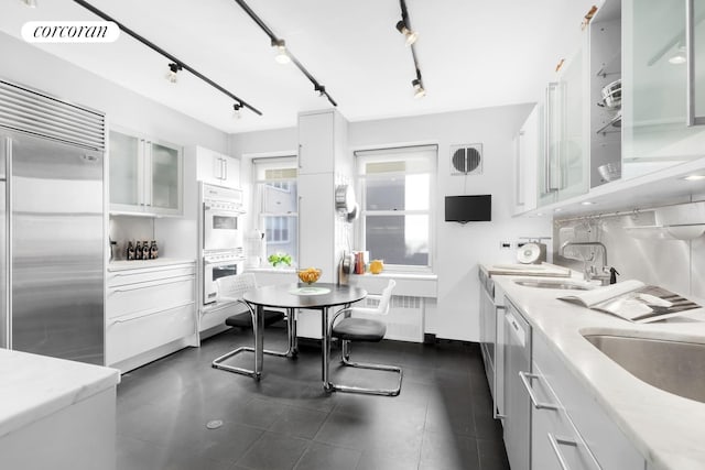 kitchen with white cabinets, glass insert cabinets, light countertops, and built in fridge