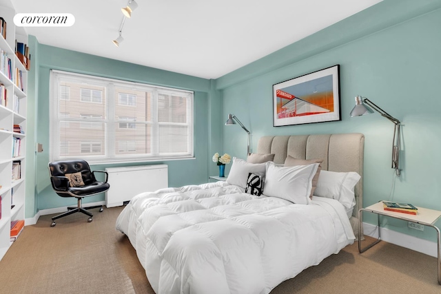 bedroom featuring visible vents, radiator heating unit, carpet flooring, track lighting, and baseboards