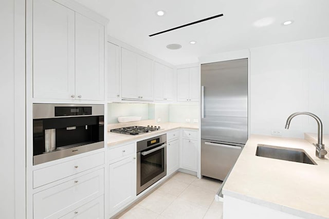 kitchen with light tile patterned flooring, sink, extractor fan, white cabinetry, and stainless steel appliances