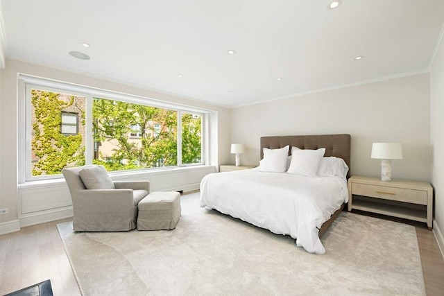 bedroom with ornamental molding, multiple windows, and light hardwood / wood-style flooring