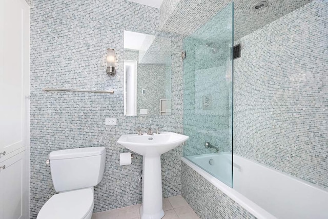 full bathroom featuring sink, tile walls, tile patterned floors, toilet, and tiled shower / bath