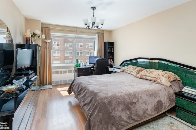 bedroom featuring wood finished floors, radiator, and a chandelier