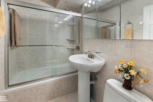 full bath featuring toilet, tiled shower / bath, and tile walls