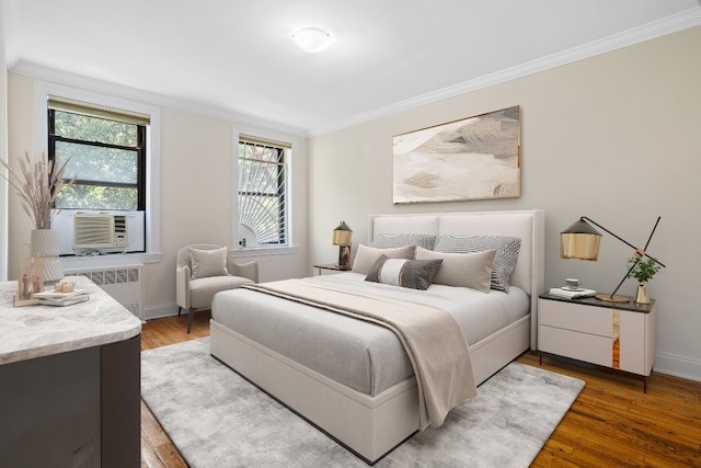 bedroom featuring ornamental molding, cooling unit, hardwood / wood-style flooring, and radiator heating unit