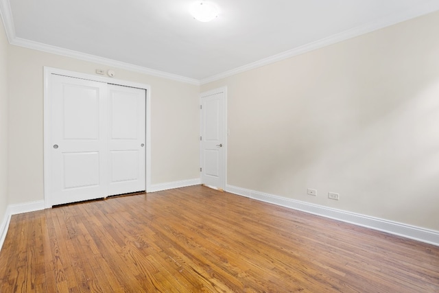 unfurnished bedroom featuring hardwood / wood-style floors, a closet, and ornamental molding