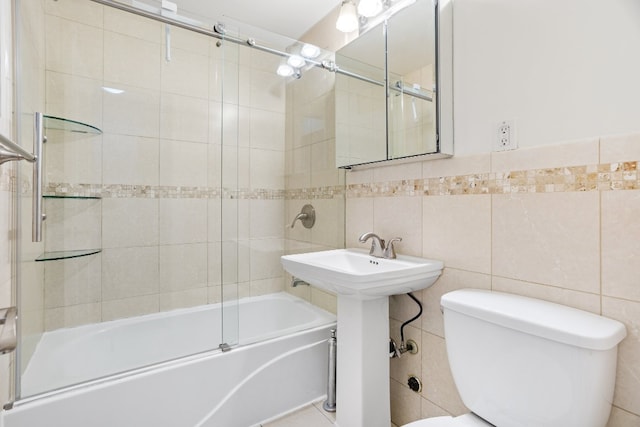 full bathroom featuring toilet, tile walls, enclosed tub / shower combo, and sink