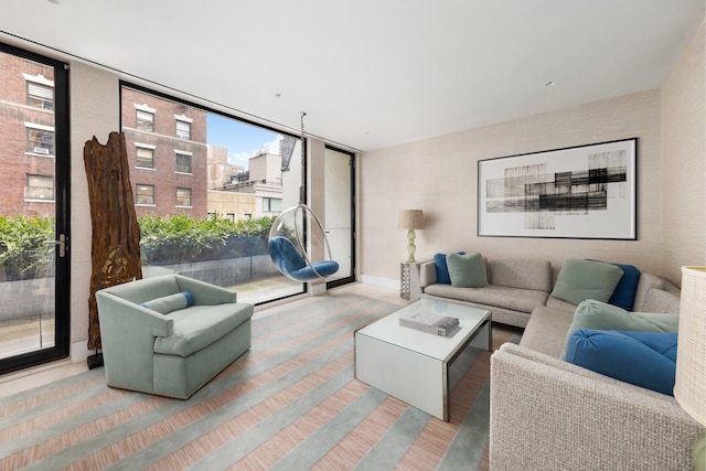 living area featuring baseboards, a wall of windows, and wood finished floors