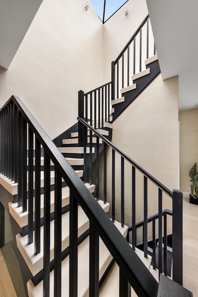 stairs with a high ceiling and wood finished floors