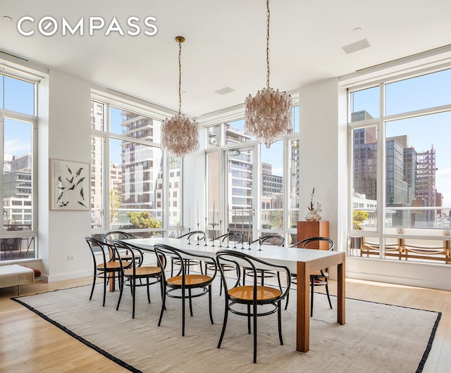 dining area with a notable chandelier, a city view, wood finished floors, and a healthy amount of sunlight