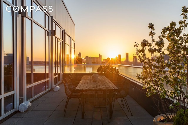 balcony featuring outdoor dining area, a water view, and a city view