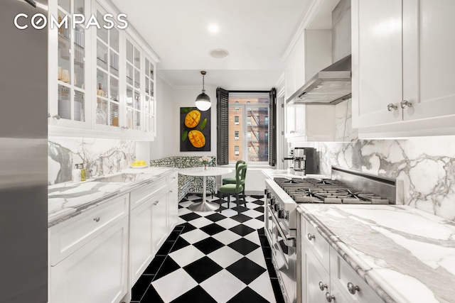 kitchen with dark floors, wall chimney exhaust hood, high end stainless steel range oven, and white cabinetry