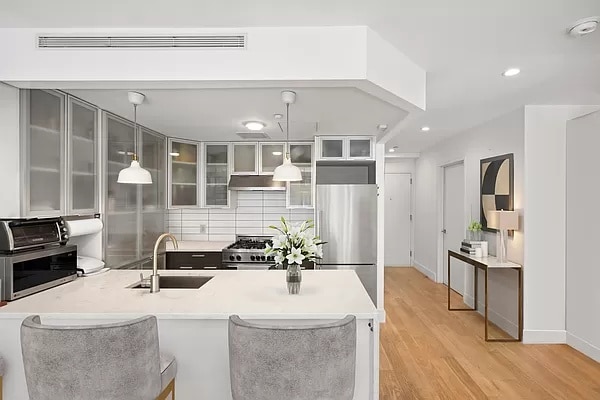 kitchen with stainless steel refrigerator, decorative light fixtures, sink, decorative backsplash, and light hardwood / wood-style floors