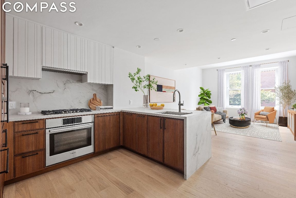 kitchen with white cabinetry, sink, light hardwood / wood-style flooring, and stainless steel appliances