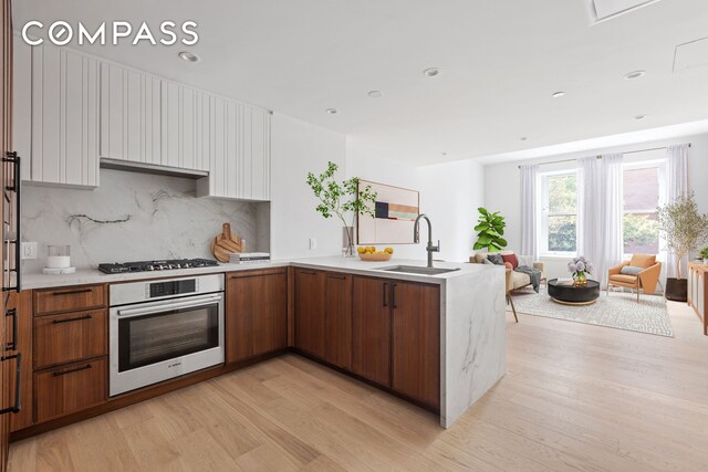 kitchen featuring stainless steel appliances, light hardwood / wood-style flooring, tasteful backsplash, and sink