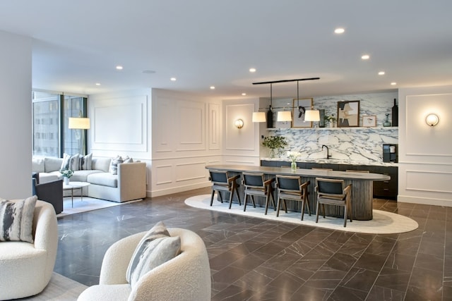 indoor wet bar featuring dark marble finish flooring, recessed lighting, a decorative wall, and hanging light fixtures
