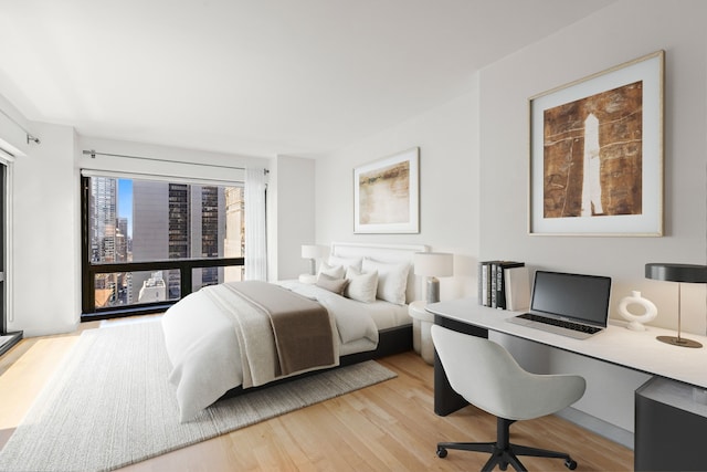 bedroom featuring light wood-style floors and an office area