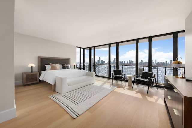 100 Vandam St Unit 20-A, New York City, NY 10013 - bedroom with light wood finished floors, a wall of windows, a skyline view, access to outside, and baseboards