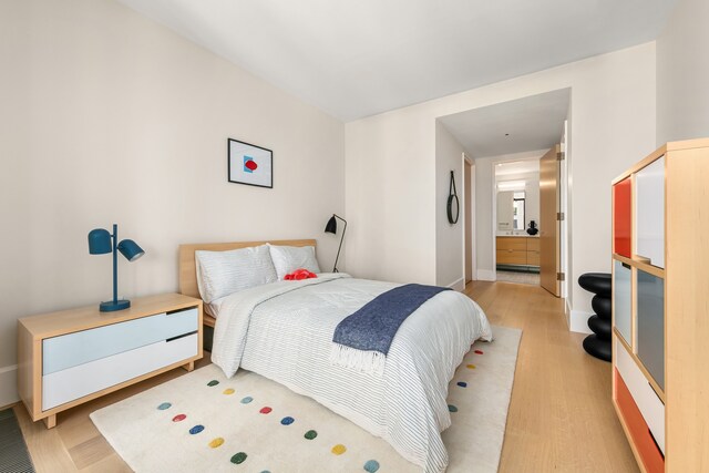 100 Vandam St Unit 20-A, New York City, NY 10013 - bedroom with light wood-style flooring, connected bathroom, and baseboards