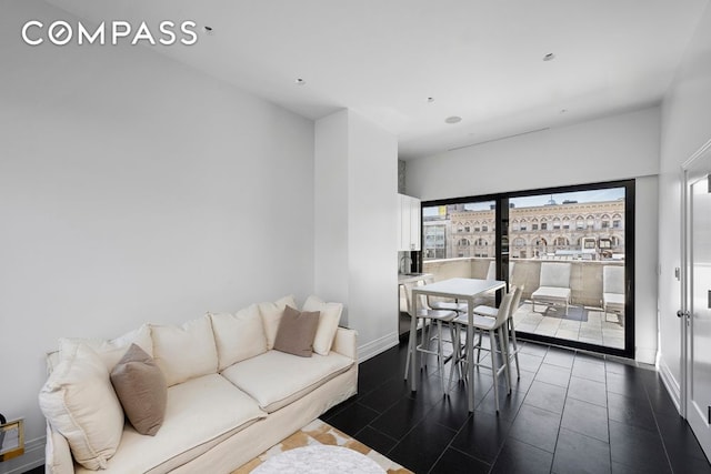 living area featuring a view of city, dark tile patterned flooring, and baseboards