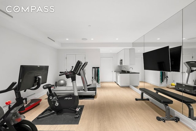 workout room featuring light wood-style floors, recessed lighting, and baseboards