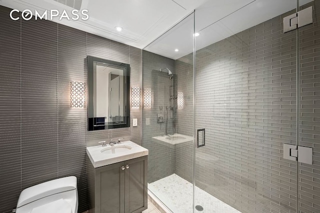 bathroom with toilet, vanity, tile walls, ornamental molding, and a stall shower