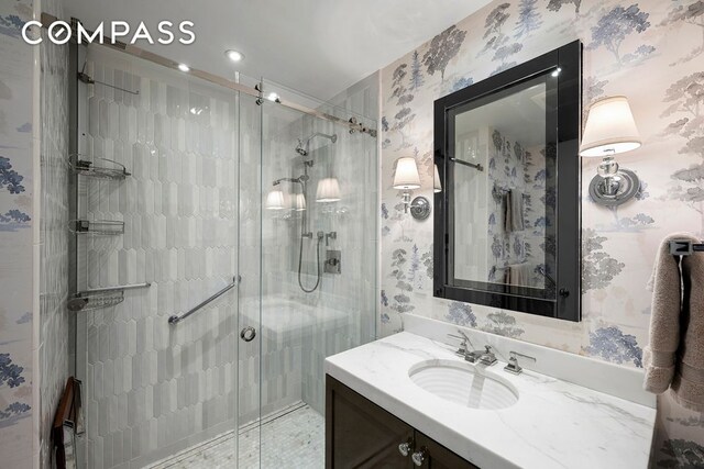 bathroom featuring a stall shower, wallpapered walls, and vanity