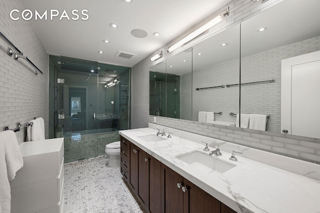 bathroom featuring toilet, a sink, tile walls, and a shower stall