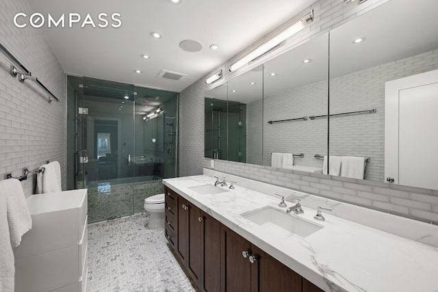 full bath featuring toilet, a shower stall, double vanity, tile walls, and recessed lighting
