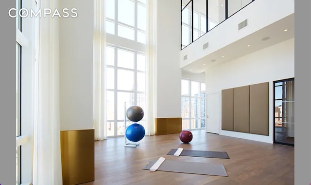 workout room with hardwood / wood-style floors and a towering ceiling