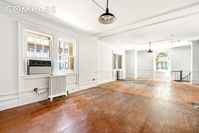 spare room with crown molding, hardwood / wood-style flooring, radiator heating unit, and a decorative wall