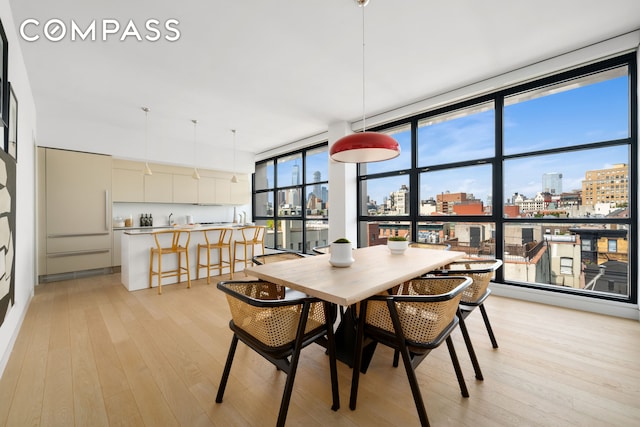 dining space featuring expansive windows, light wood finished floors, and a city view