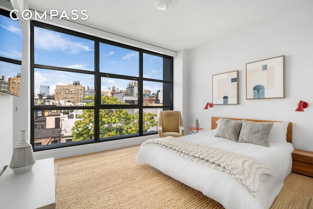 bedroom with a view of city and wood finished floors