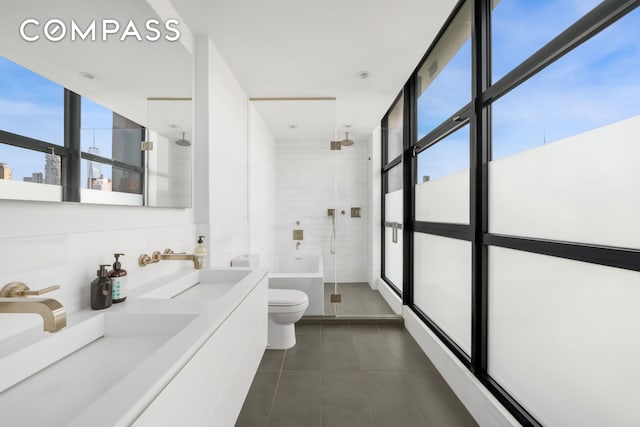 bathroom featuring double vanity, toilet, a sink, a shower stall, and tile patterned flooring