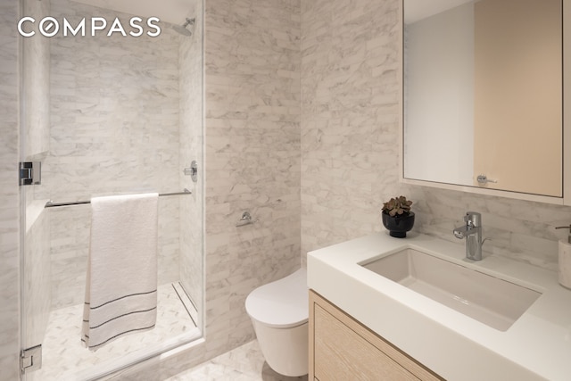 full bathroom with toilet, vanity, a stall shower, marble finish floor, and tile walls