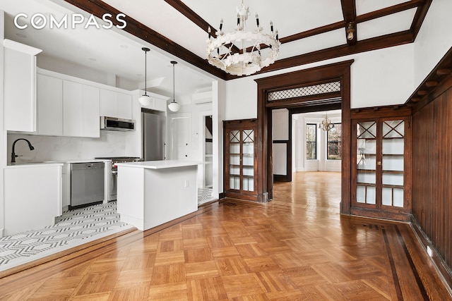 kitchen featuring a chandelier, high quality appliances, light countertops, white cabinetry, and a sink