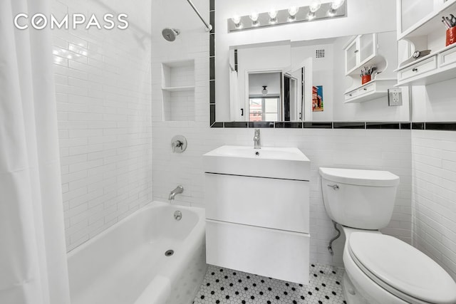 full bath with toilet, visible vents, tile walls, wainscoting, and tub / shower combination