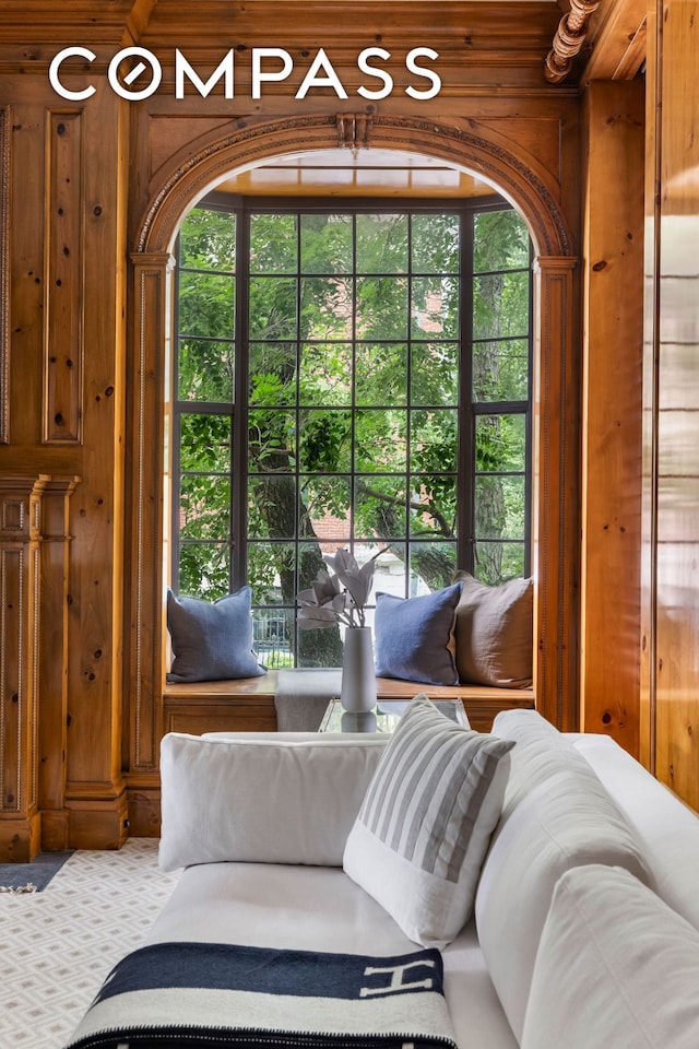 interior space featuring carpet, a healthy amount of sunlight, and wooden walls