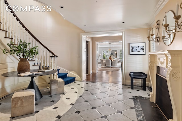 entryway featuring baseboards, stairs, ornamental molding, and a fireplace