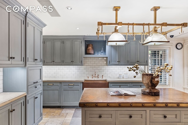 kitchen featuring gray cabinets, tasteful backsplash, and a sink
