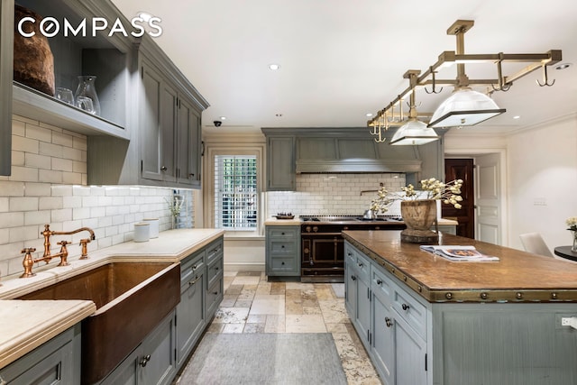 kitchen with a center island, a sink, decorative backsplash, gray cabinetry, and stone tile flooring