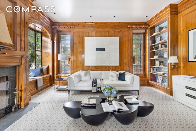 carpeted living room with a fireplace with flush hearth and wooden walls