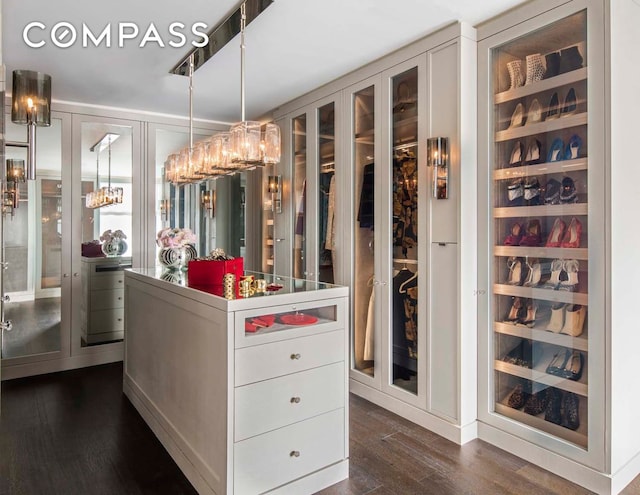 walk in closet featuring a chandelier and dark wood finished floors