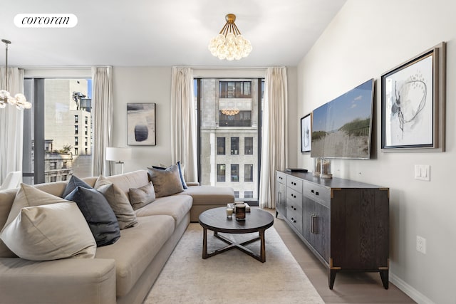 living room featuring light wood finished floors, baseboards, visible vents, and a notable chandelier