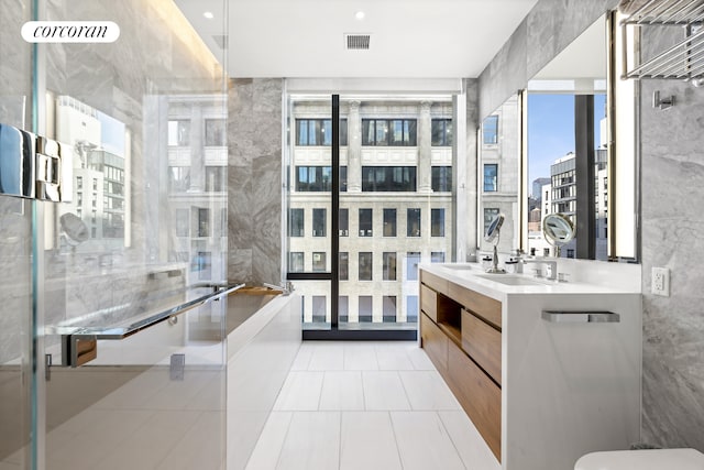 full bath with double vanity, tile patterned floors, visible vents, and tile walls